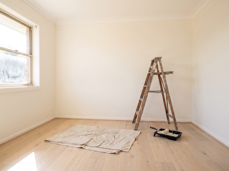 An empty room with fresh paint, new floors and a step ladder during light preparation work